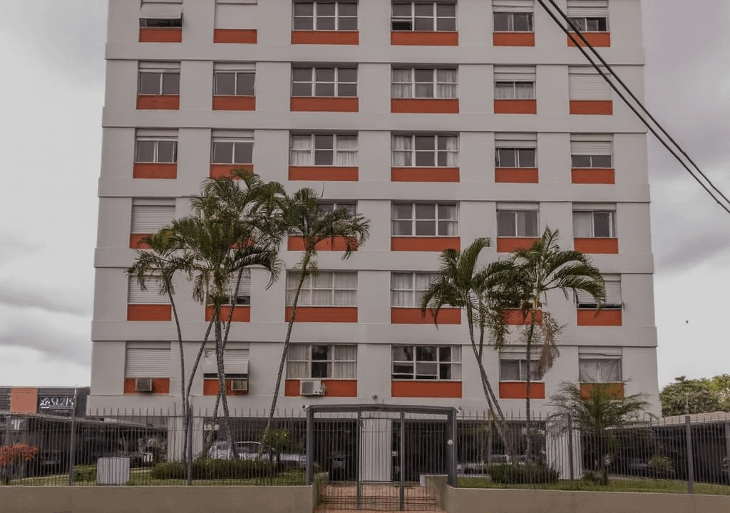 Prédio moderno com palmeiras e céu nublado